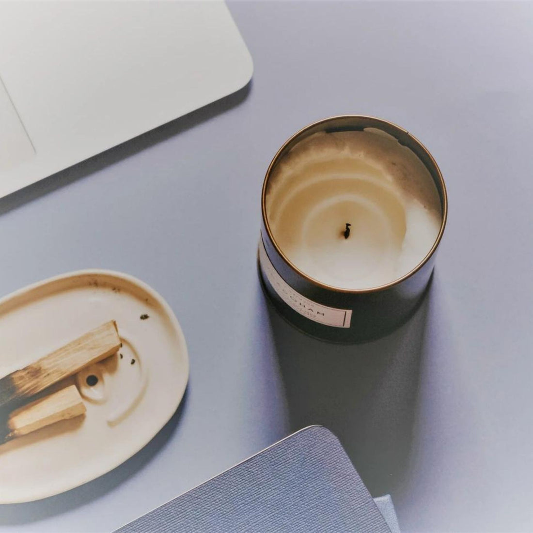 top view of a candle with tunneling next to lighting sticks and a notebook