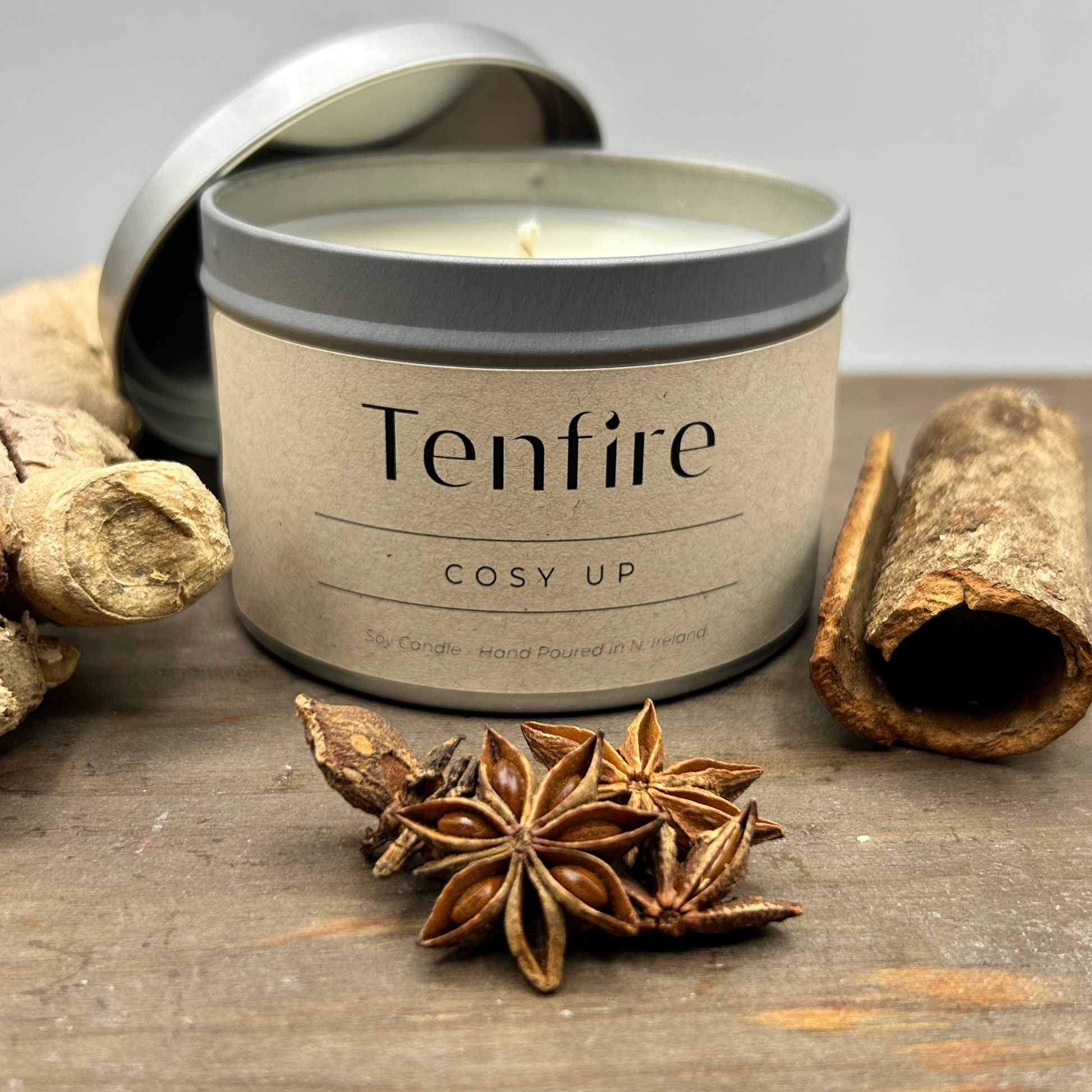 Open candle tin called cosy up with ginger, star anise and cinammon pieces nearby
