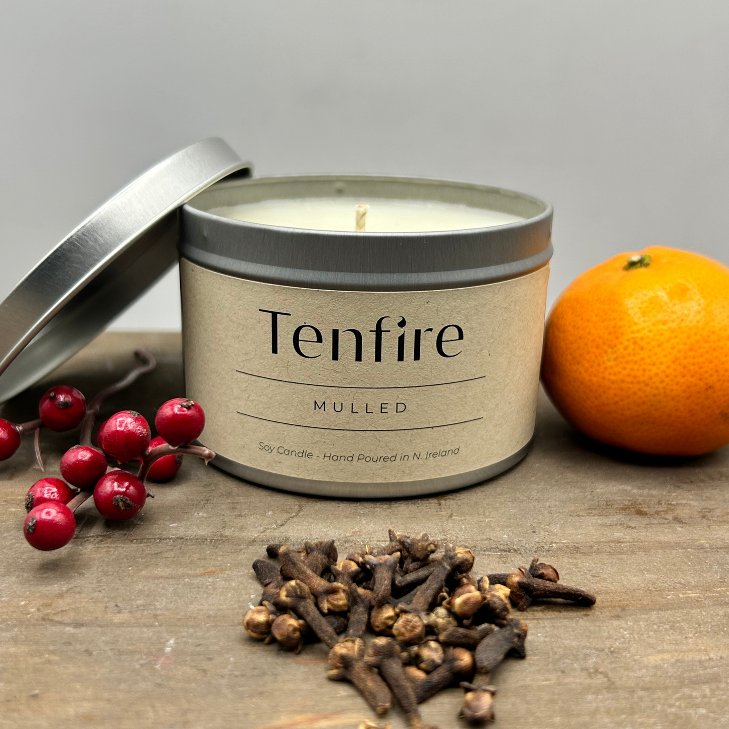open candle tin called mulled with berries, cloves and orange next to it