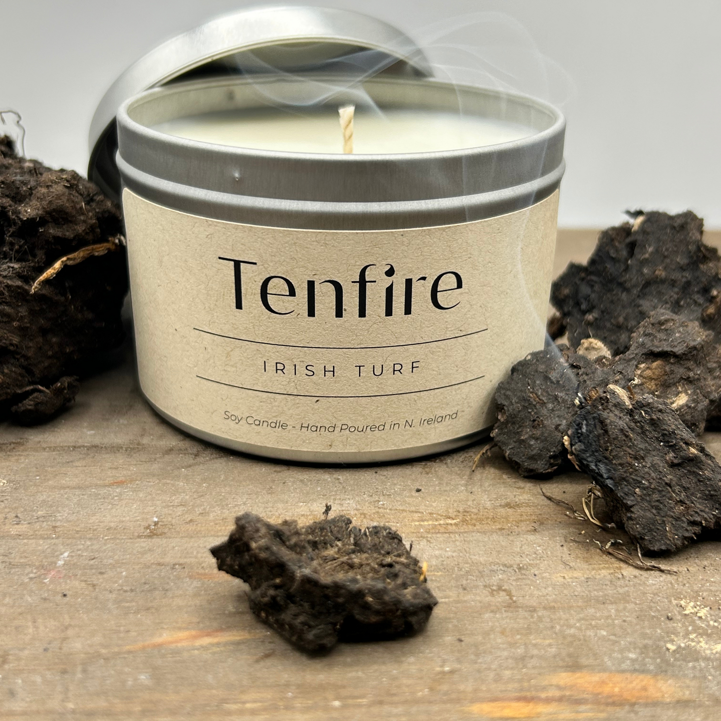 open candle tin called irish turf with pieces of turf and a wisp of smoke nearby
