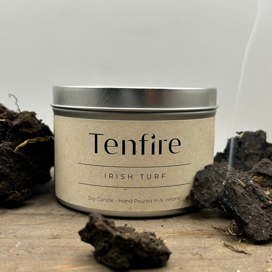 soy wax candle tin called irish turf with turf pieces and wisp of smoke nearby